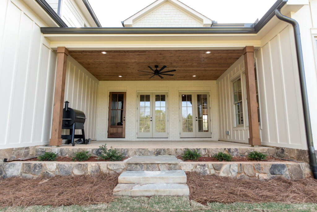 Brouwer Building Group custom home covered back porch with wood ceiling, ceiling fan, and stone steps