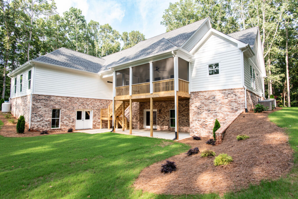 Brouwer Building Group custom home rear exterior with screened porch, brick foundation, and landscaped backyard